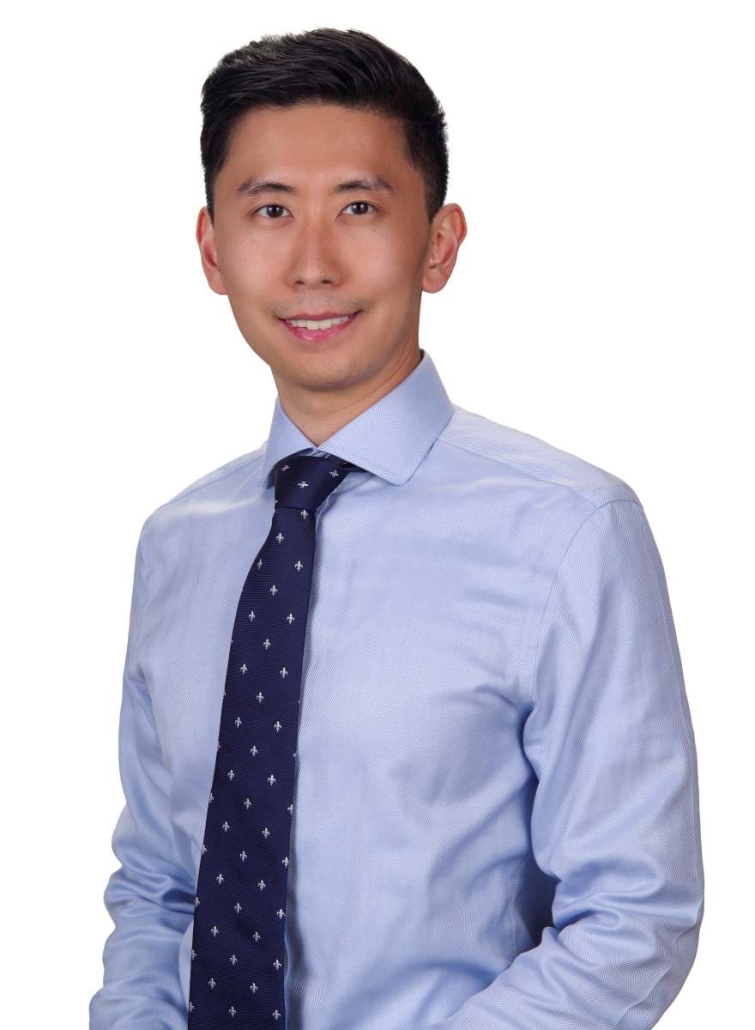 Professional headshot of male physician wearing a light blue shirt and navy patterned tie, smiling against a white background.